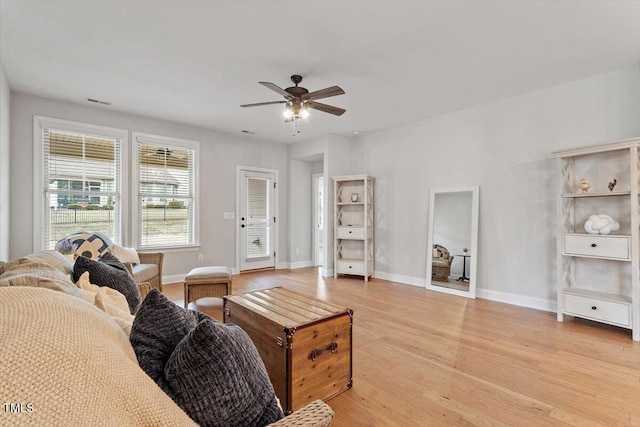 living area featuring light wood-type flooring, a ceiling fan, and baseboards