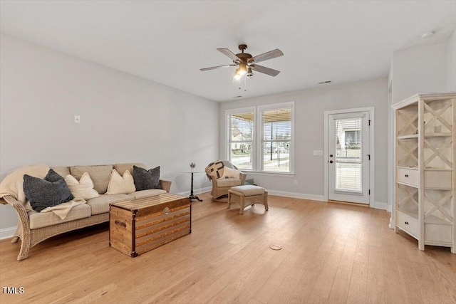 living area with baseboards, ceiling fan, and light wood-style floors