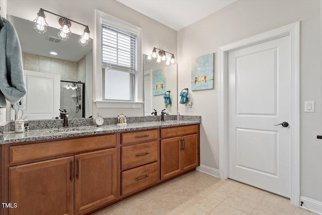 full bath featuring double vanity, baseboards, visible vents, a shower stall, and a sink