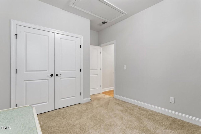 unfurnished bedroom with light carpet, visible vents, baseboards, a closet, and attic access