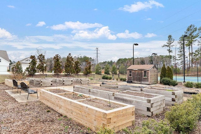 view of yard featuring a shed, an outdoor structure, a vegetable garden, and fence