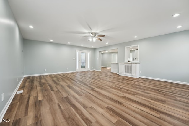 unfurnished living room with ceiling fan, baseboards, wood finished floors, and recessed lighting