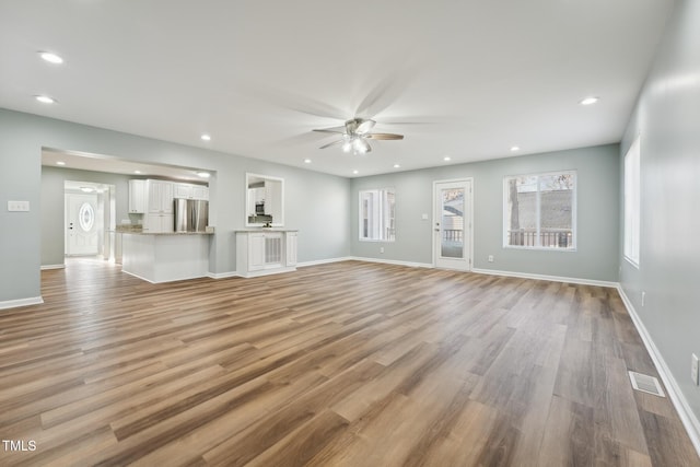 unfurnished living room featuring recessed lighting, visible vents, baseboards, a ceiling fan, and light wood-style floors