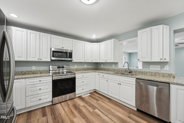 kitchen featuring stainless steel appliances, recessed lighting, light wood-style flooring, white cabinets, and a sink