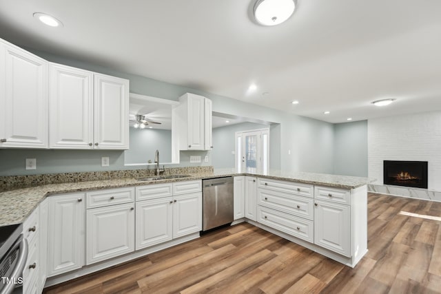 kitchen with appliances with stainless steel finishes, a fireplace, a sink, and light wood finished floors