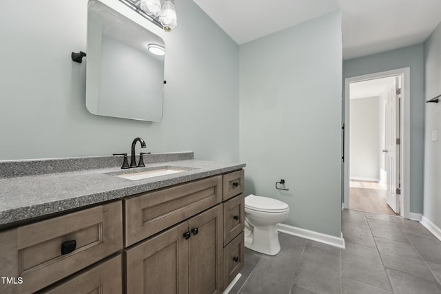 bathroom featuring toilet, tile patterned flooring, baseboards, and vanity