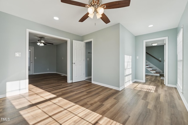 unfurnished room featuring recessed lighting, stairway, baseboards, and wood finished floors