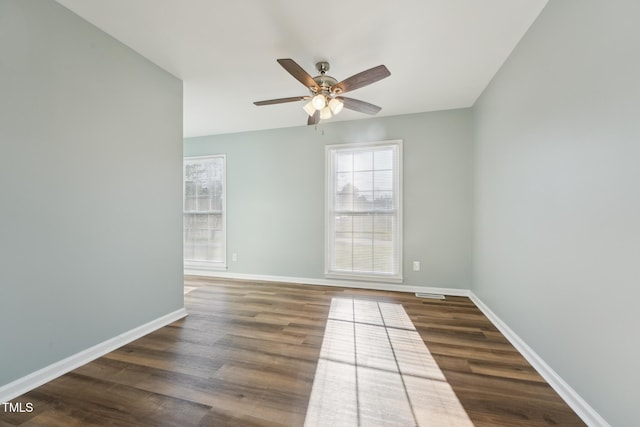 spare room with dark wood-type flooring, a healthy amount of sunlight, and baseboards