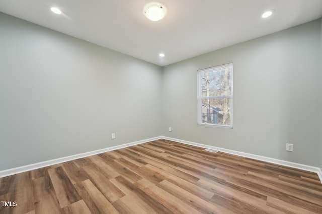 spare room featuring baseboards, wood finished floors, and recessed lighting