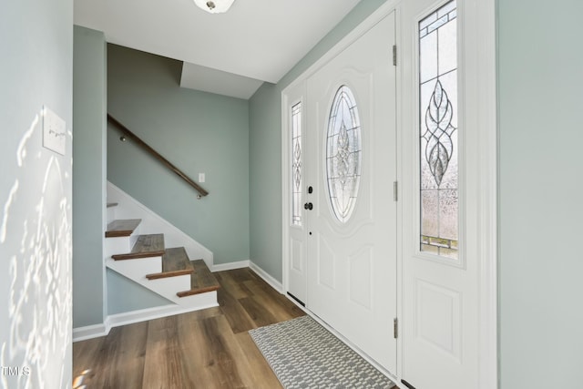 foyer entrance with stairway, baseboards, and wood finished floors