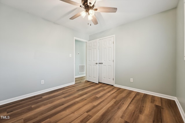 unfurnished bedroom with a closet, visible vents, a ceiling fan, wood finished floors, and baseboards