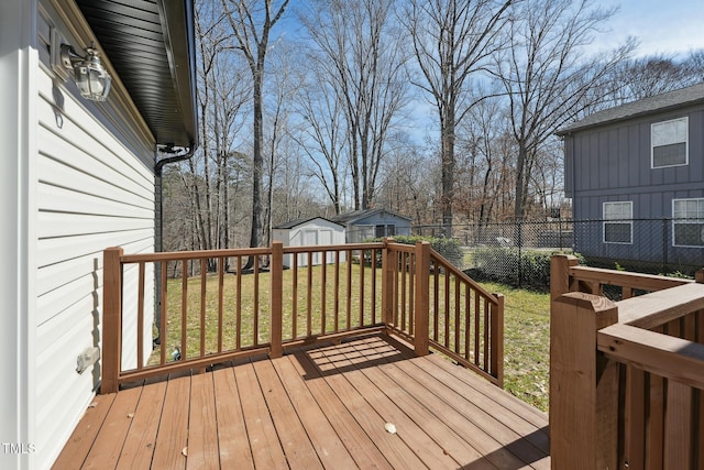 wooden deck featuring a yard, an outbuilding, fence, and a storage unit