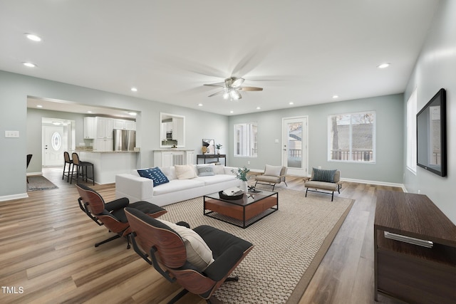 living area featuring baseboards, ceiling fan, light wood finished floors, and recessed lighting