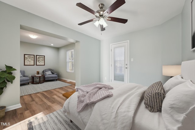 bedroom with ceiling fan, wood finished floors, and baseboards