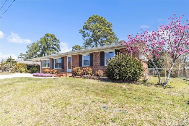 ranch-style home with a front yard, fence, brick siding, and driveway