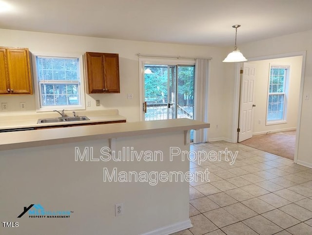 kitchen with a wealth of natural light, brown cabinets, a sink, and light countertops