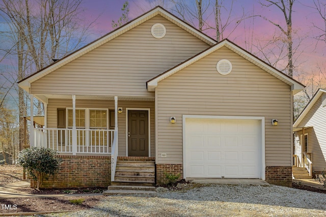 view of front of home featuring a garage, covered porch, and gravel driveway