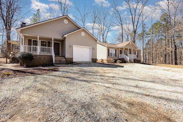 ranch-style house with covered porch, an attached garage, and gravel driveway