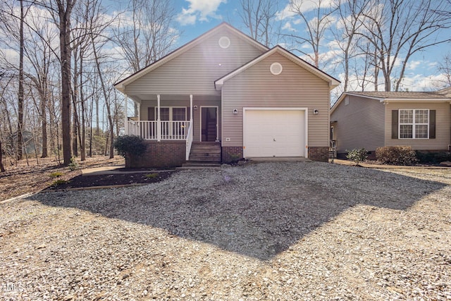 view of front of property featuring gravel driveway, covered porch, and a garage