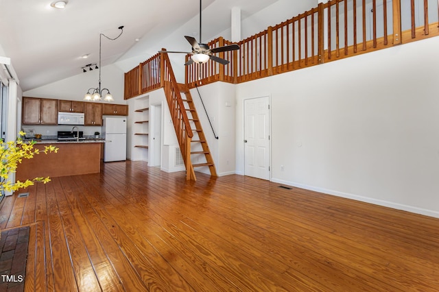 unfurnished living room featuring dark wood-style flooring, stairway, a sink, baseboards, and ceiling fan with notable chandelier