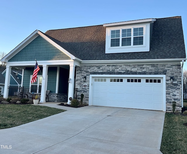 craftsman inspired home with covered porch, a garage, and a front lawn