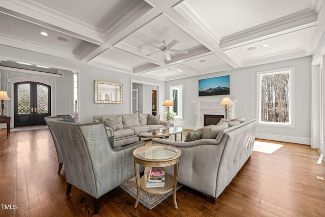 living area with beamed ceiling, coffered ceiling, and ceiling fan