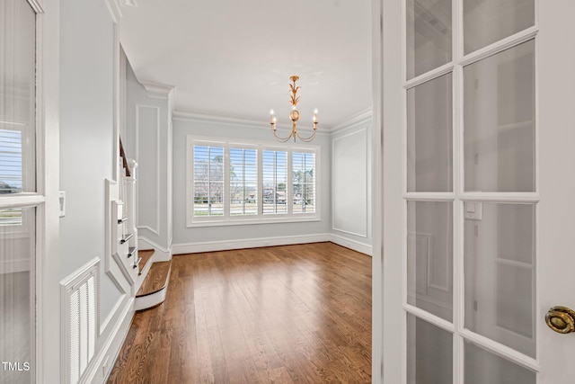 interior space with a notable chandelier, crown molding, visible vents, and wood finished floors