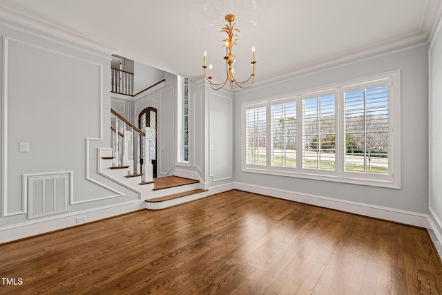 interior space featuring a notable chandelier, wood finished floors, visible vents, and ornamental molding