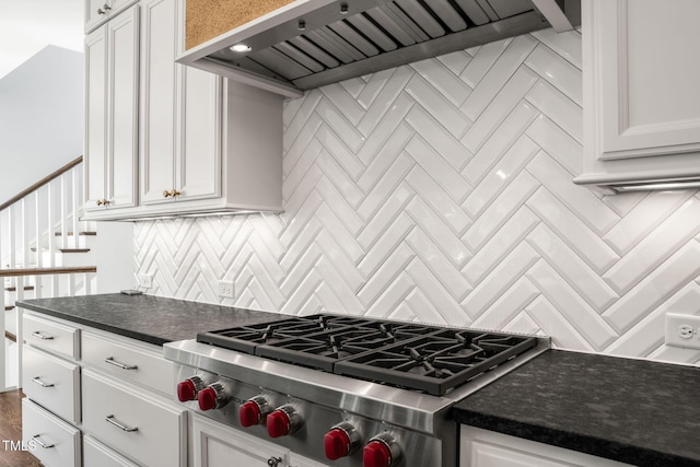 kitchen with premium range hood, dark countertops, stainless steel gas stovetop, white cabinets, and decorative backsplash