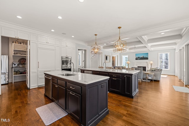 kitchen with a sink, open floor plan, a center island with sink, and white cabinets