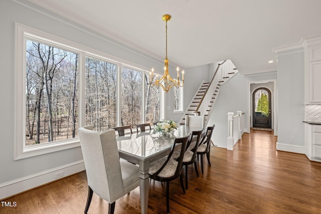 dining room with ornamental molding, baseboards, an inviting chandelier, and wood finished floors