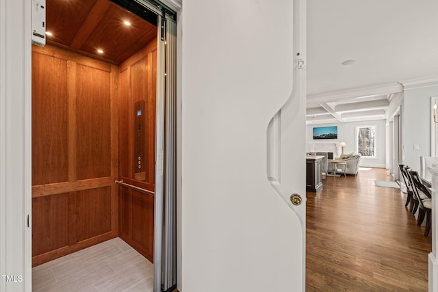 hallway with wood finished floors, coffered ceiling, elevator, recessed lighting, and beamed ceiling