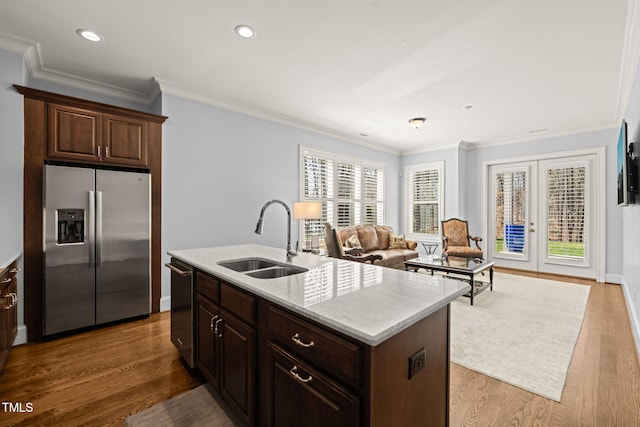 kitchen featuring dishwashing machine, plenty of natural light, ornamental molding, a sink, and stainless steel fridge