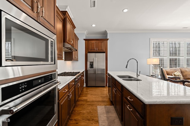 kitchen with visible vents, an island with sink, ornamental molding, stainless steel appliances, and a sink