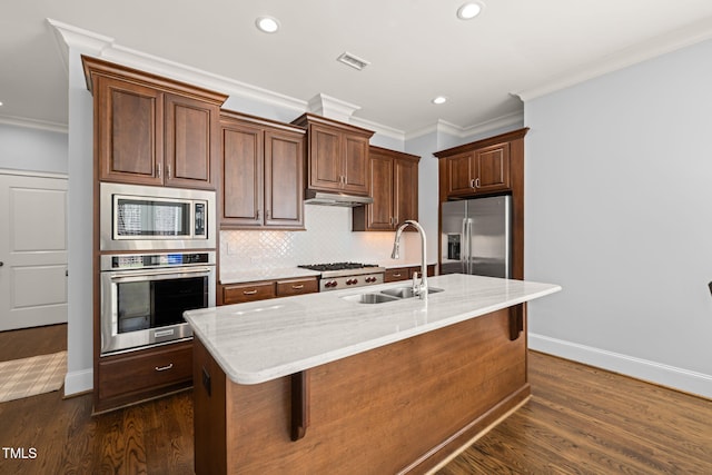 kitchen with a sink, under cabinet range hood, backsplash, appliances with stainless steel finishes, and dark wood-style flooring