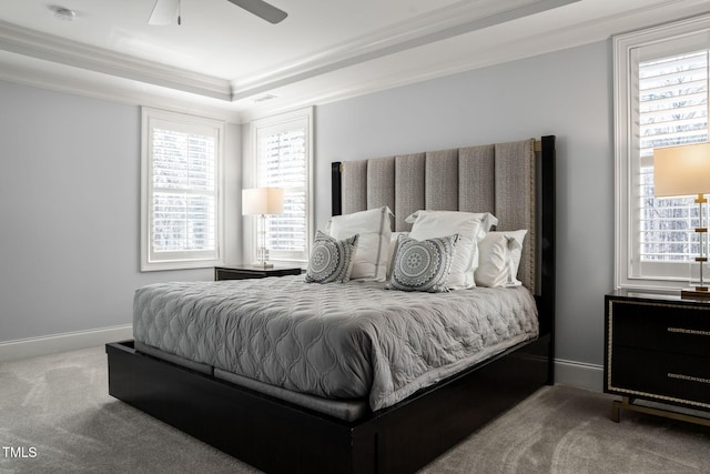 carpeted bedroom featuring a tray ceiling, baseboards, a ceiling fan, and crown molding