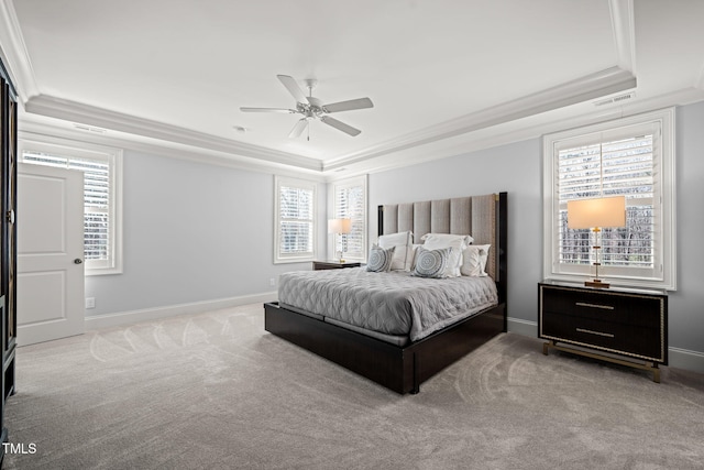 carpeted bedroom featuring a tray ceiling, multiple windows, and ornamental molding