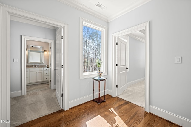 corridor featuring wood finished floors, baseboards, and ornamental molding