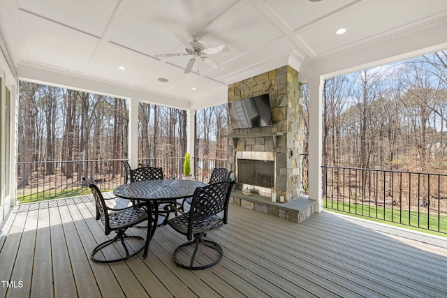 wooden deck featuring outdoor dining area, an outdoor stone fireplace, and a ceiling fan