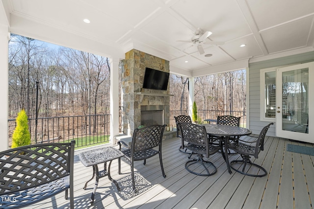 wooden terrace with outdoor dining area, an outdoor stone fireplace, and ceiling fan