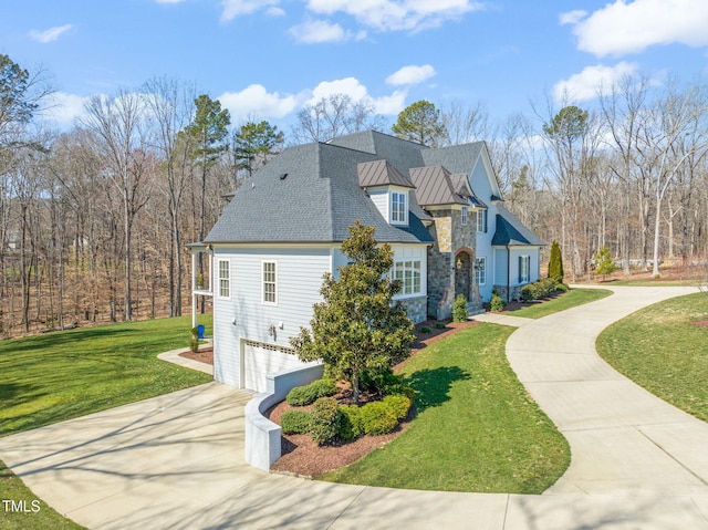 view of side of home featuring a lawn, a standing seam roof, stone siding, concrete driveway, and an attached garage