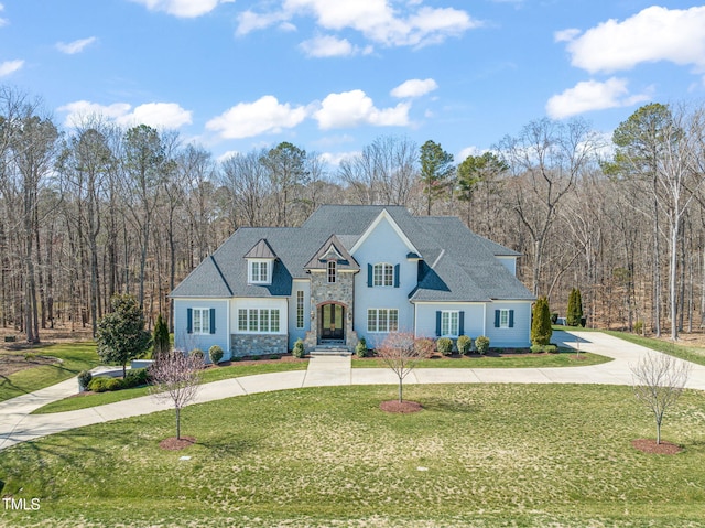 view of front of property featuring stone siding, curved driveway, and a front yard