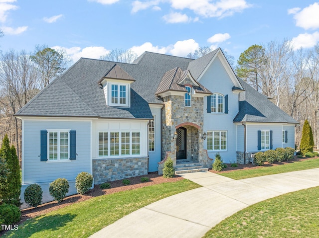 view of front of property featuring stone siding, a front lawn, and roof with shingles