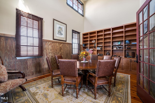 dining space featuring a wealth of natural light, a wainscoted wall, wood finished floors, and wood walls