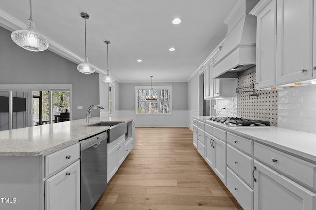 kitchen featuring a wainscoted wall, plenty of natural light, appliances with stainless steel finishes, white cabinetry, and crown molding