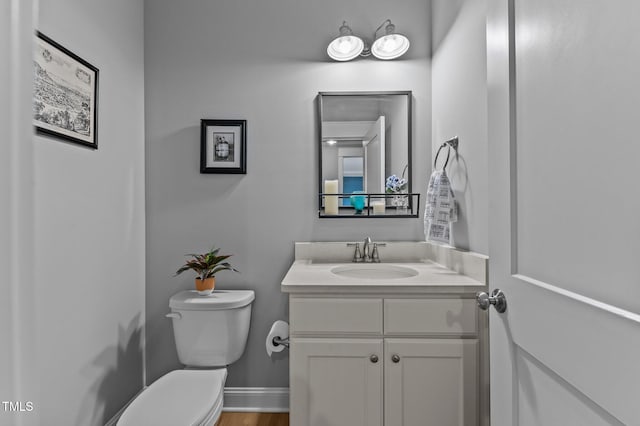 bathroom featuring toilet, vanity, and baseboards