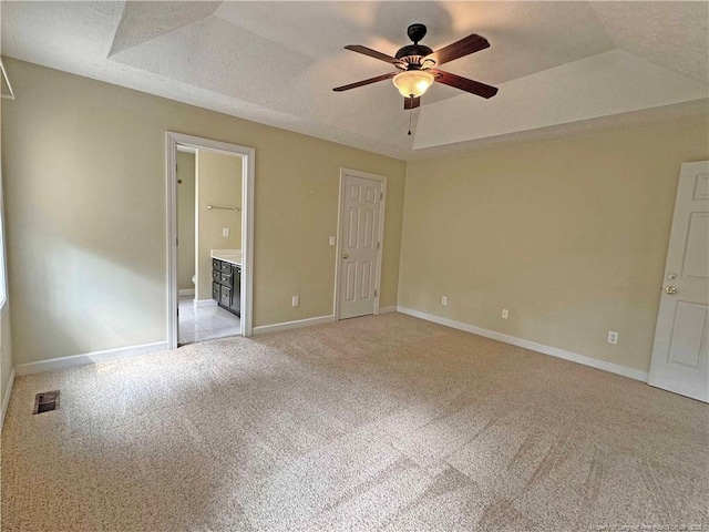 unfurnished bedroom featuring a textured ceiling, a tray ceiling, and light colored carpet