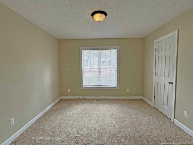 empty room with carpet flooring and a textured ceiling