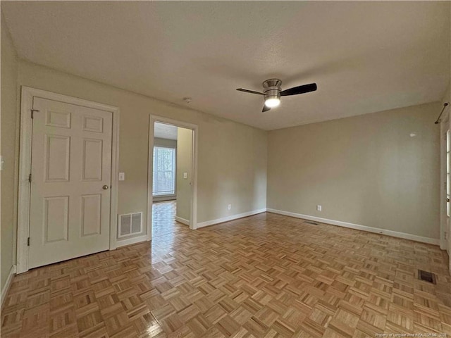 unfurnished room featuring ceiling fan, light parquet floors, and a textured ceiling