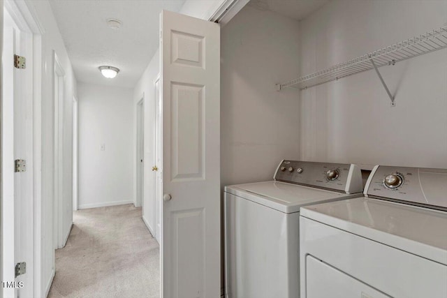 laundry room featuring laundry area, washing machine and dryer, light colored carpet, and baseboards